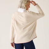 Person wearing a beige sweater with a white collar against a plain background