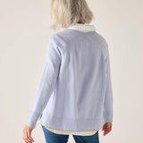 Person wearing a light blue sweater with a white collar on a beige background