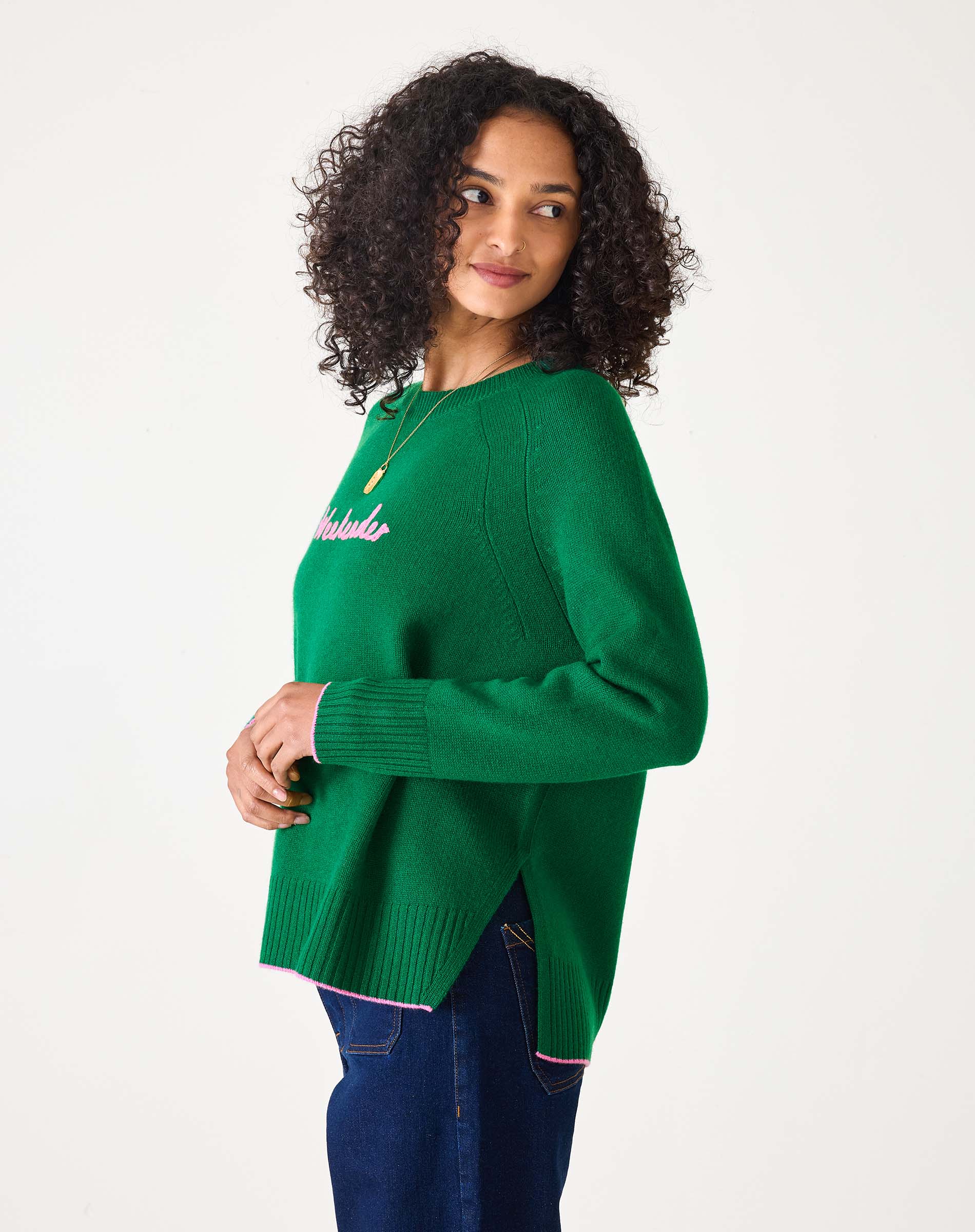 Green sweater with pink text 'Weekender' worn by a person on a white background