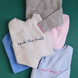 Stack of folded sweaters with text on a green background