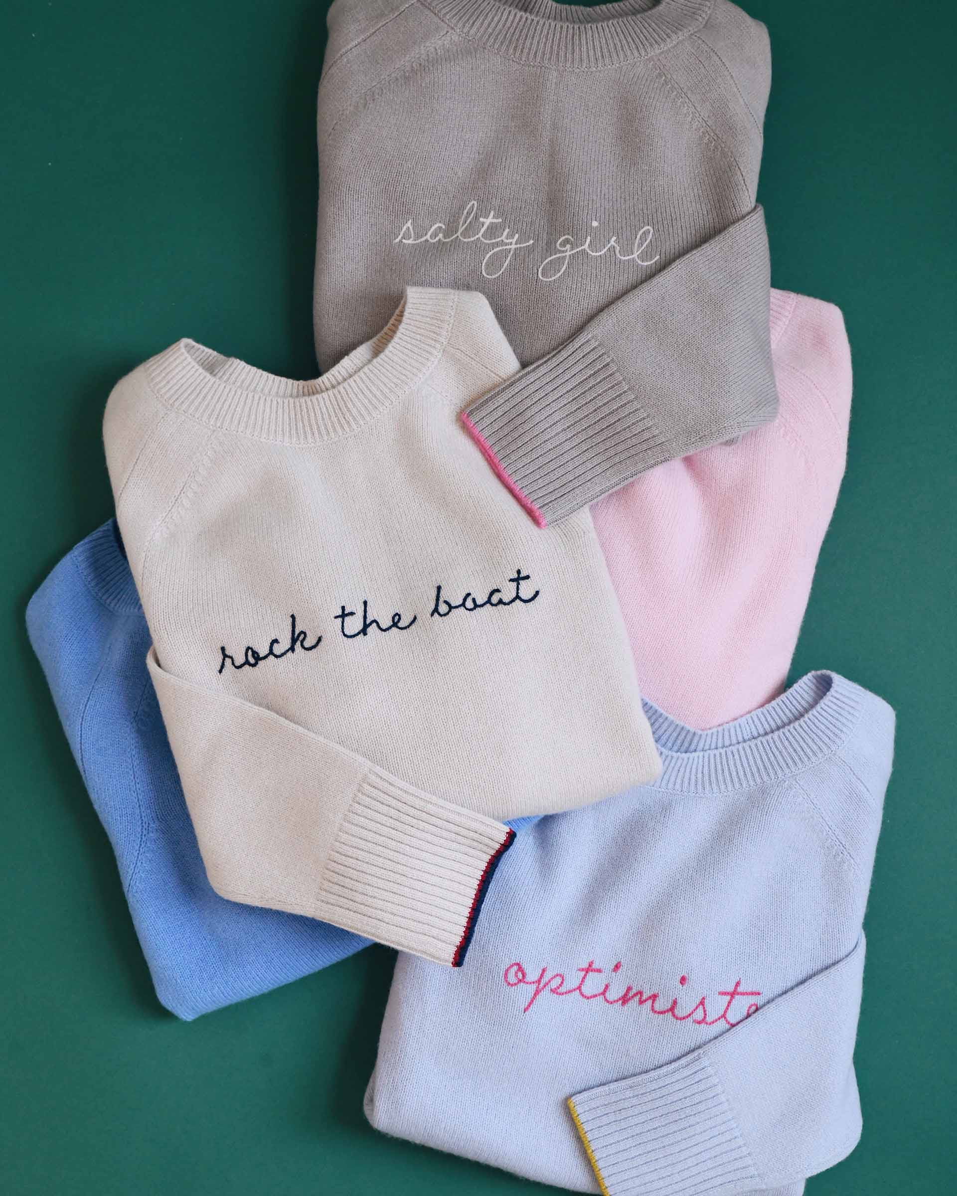 Stack of folded sweaters with text on a green background