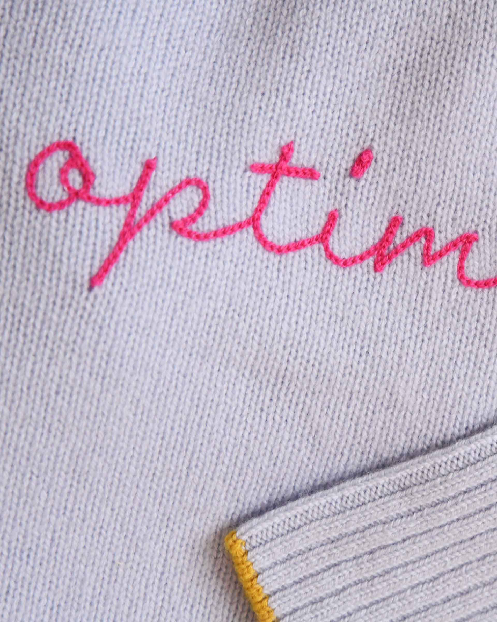 Gray fabric with pink embroidered text on a gray background