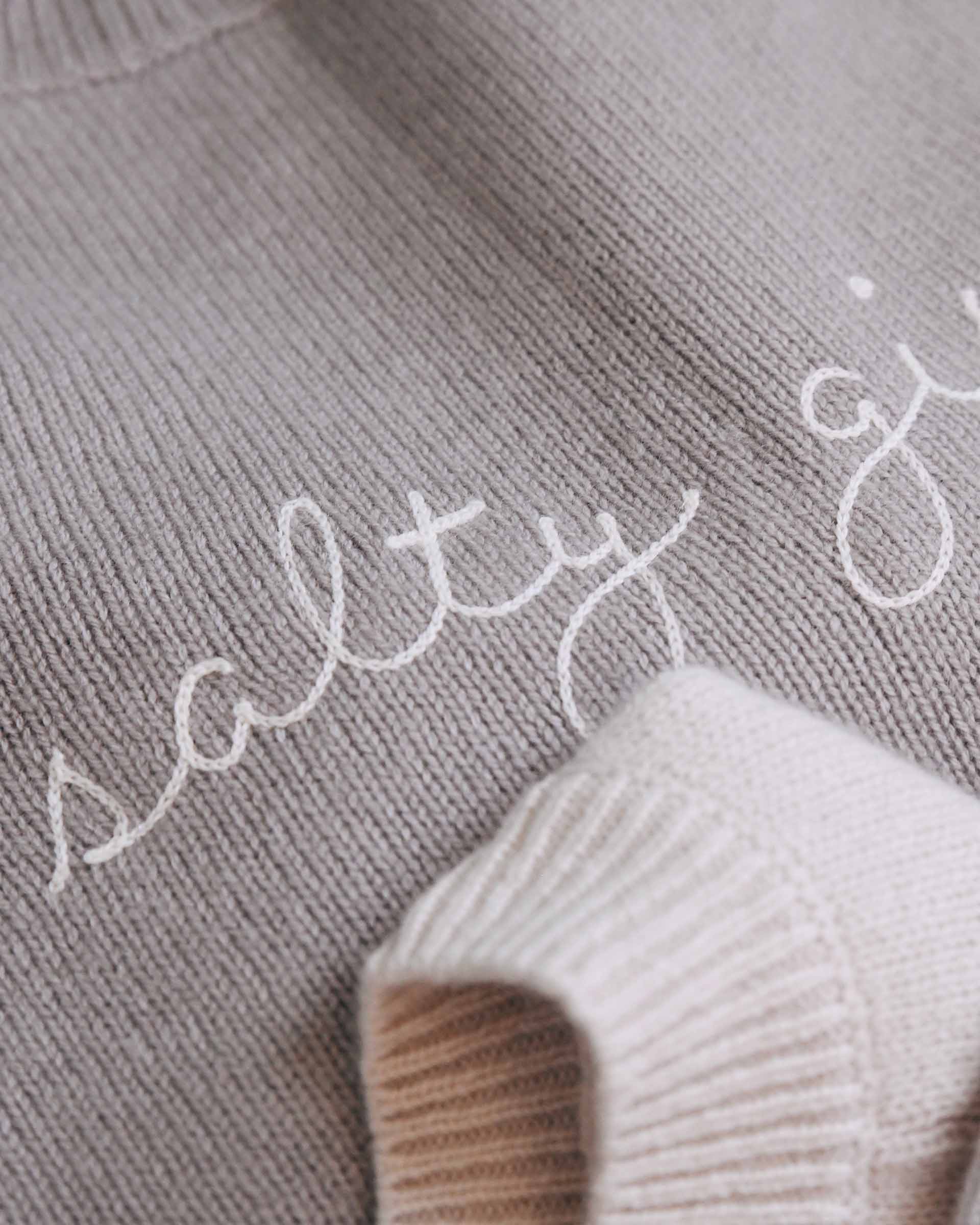 Text 'salty' embroidered on a textured fabric surface