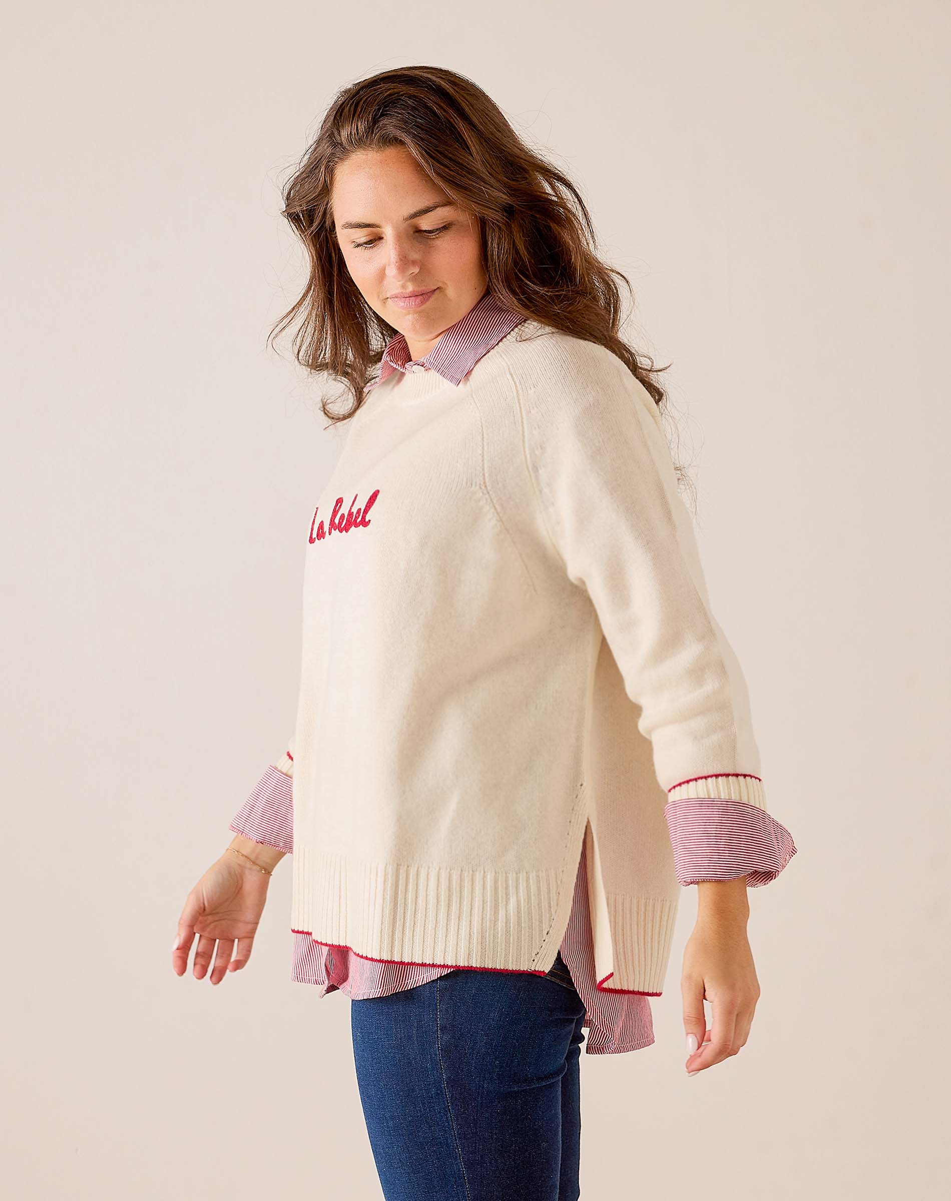 Cream knit oversized sweater with a red 'La Rebel' script graphic and side slits. Text: La Rebel