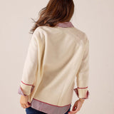 Back view of a ivory knit sweater featuring a striped contrast hem and cuffs with red trim.
