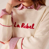 Cream knit sweater with red script and striped collar detail. Text: La Rebel