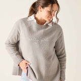 Woman wearing a gray sweater with 'salty girl' text on a plain background