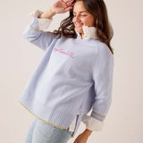 Sky blue knit sweater with ruffled neckline and 'optimiste' text on chest. Text: optimiste