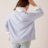 Sky blue knit sweater with a tiered hem, yellow striped trim, and white ruffled collar