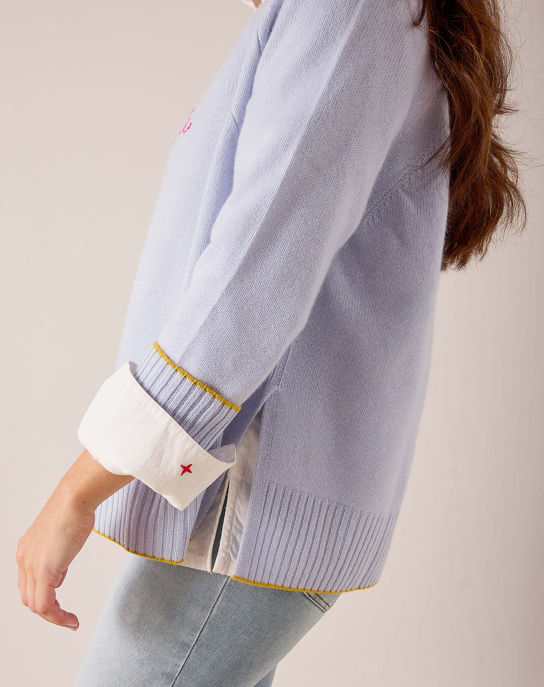 Sky blue knit sweater with white contrast cuffs and small star embroidery detail.