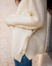 profile closeup of woman wearing mersea bari side button buttercream sweater standing against white background
