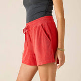 Person wearing red shorts and a black top on a beige background