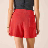 Person wearing red shorts and a dark top on a beige background