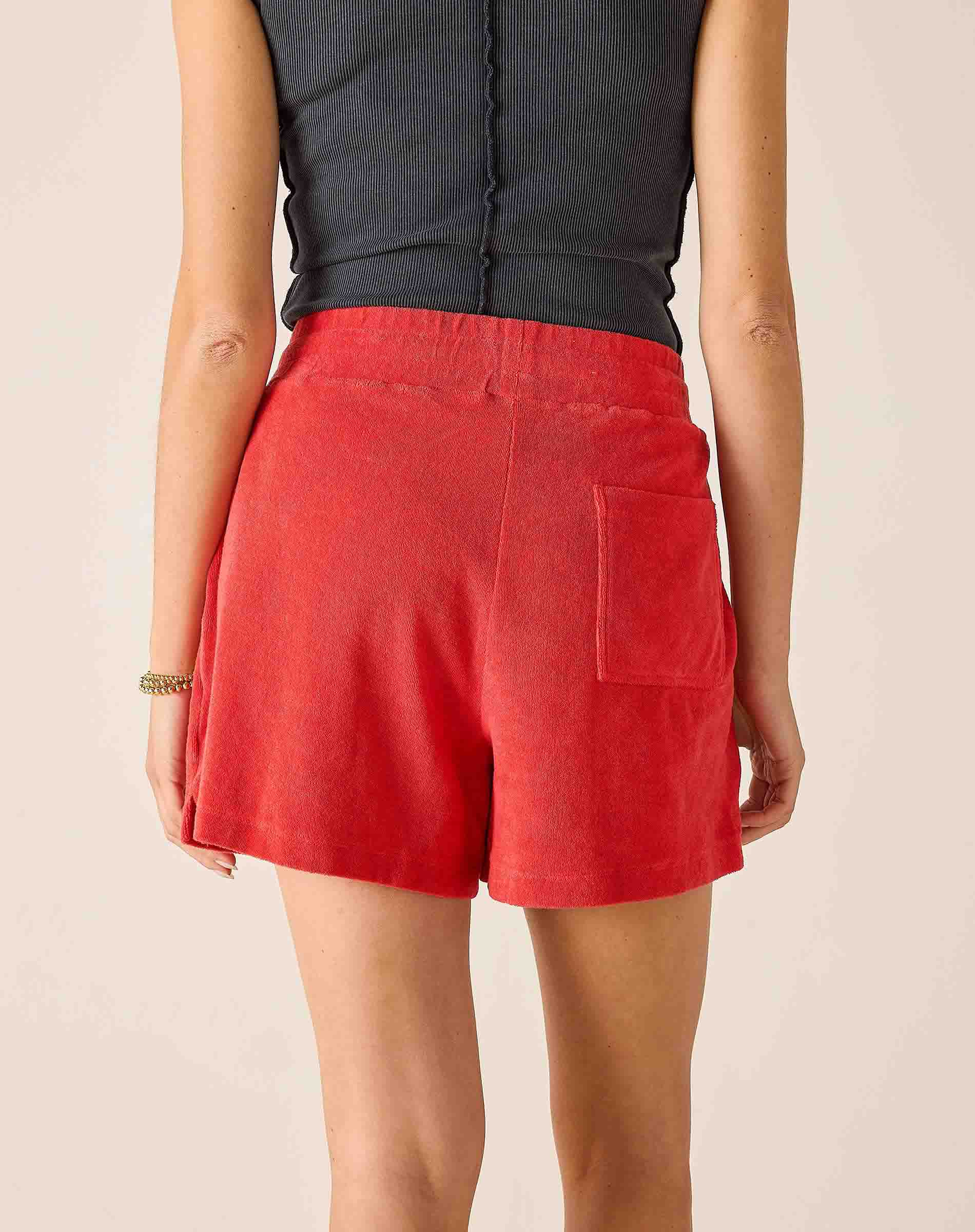 Person wearing red shorts and a dark top on a beige background