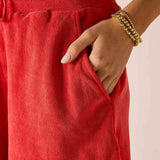 Person wearing red pants with a gold bracelet on a neutral background
