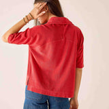 Person wearing a red jacket and blue shorts on a plain background