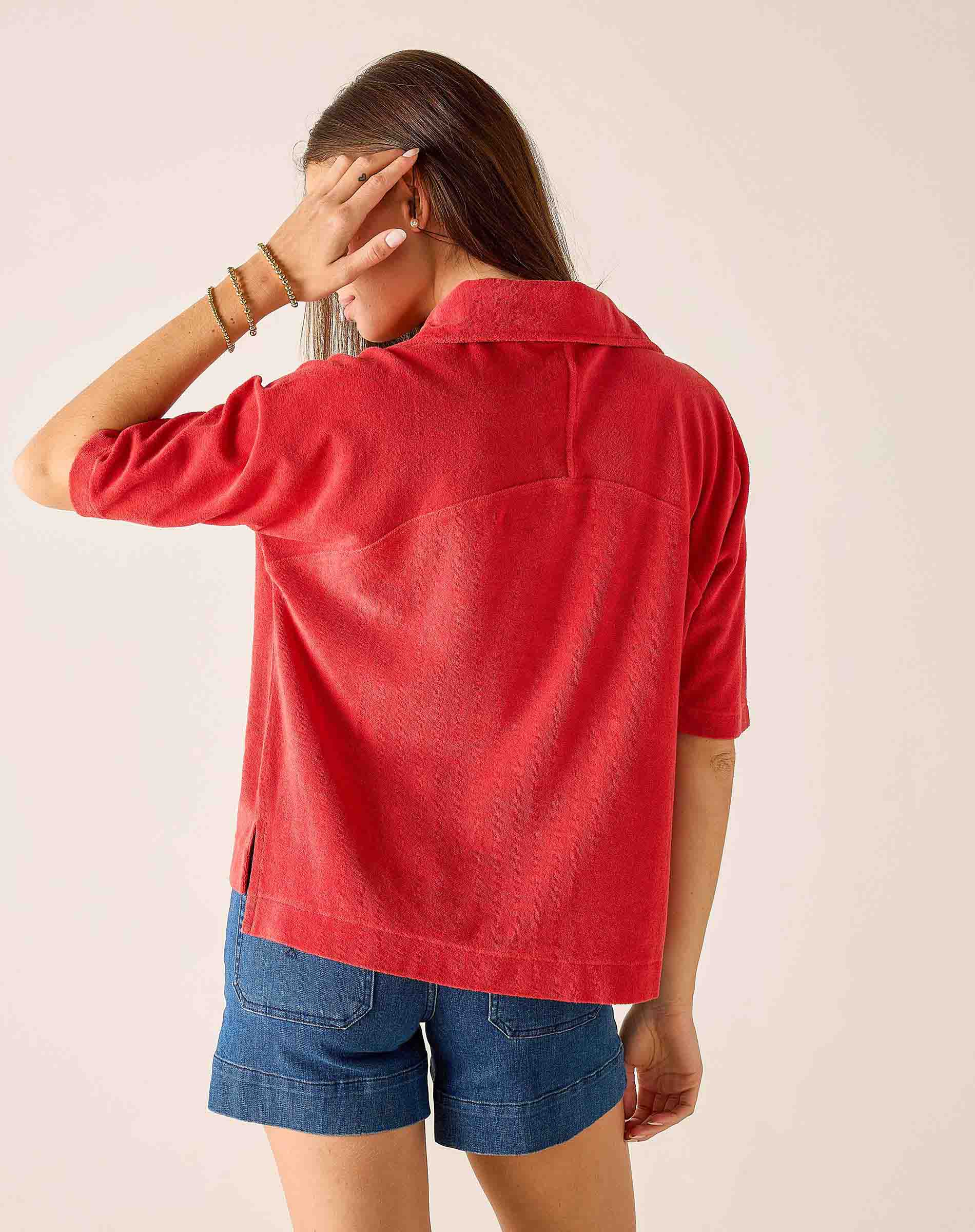 Person wearing a red jacket and blue shorts on a plain background