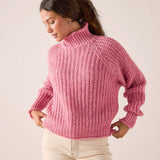 Softy pink knit turtleneck sweater with a ribbed texture and long sleeves.