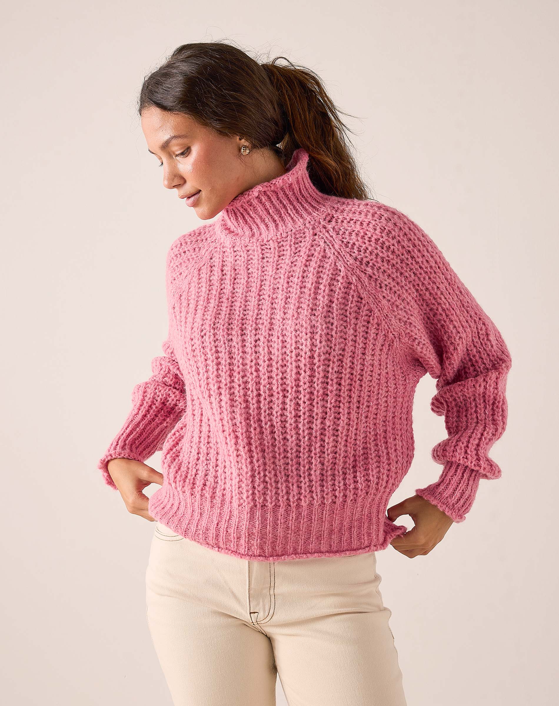 Softy pink knit turtleneck sweater with a ribbed texture and long sleeves.