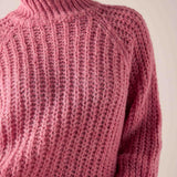 Soft pink knitted turtleneck sweater with a textured ribbed stitch.