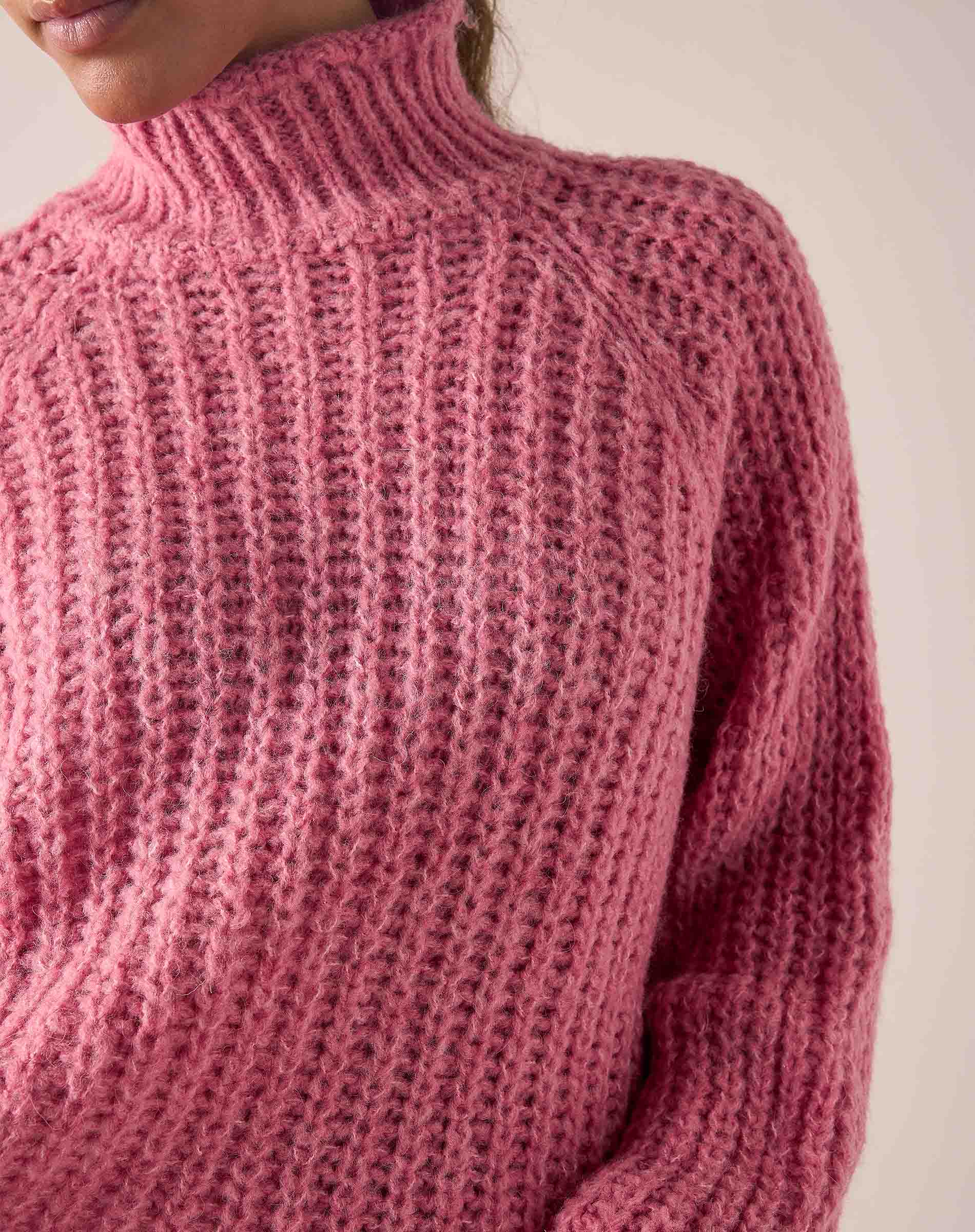 Soft pink knitted turtleneck sweater with a textured ribbed stitch.