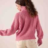 Soft pink chunky knit sweater with a high neck and wide sleeves.