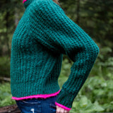 Bright emerald knit sweater with a textured weave and vibrant pink trim.