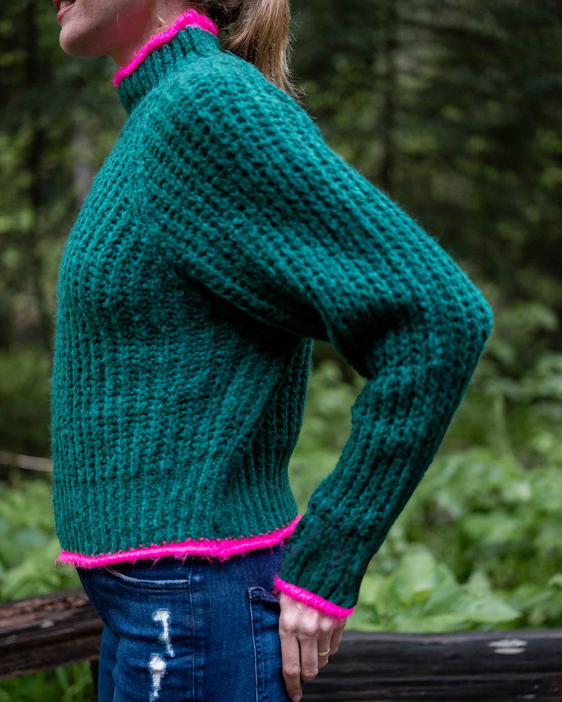 Bright emerald knit sweater with a textured weave and vibrant pink trim.