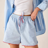 Light blue shorts with a red drawstring worn by a person on a beige background