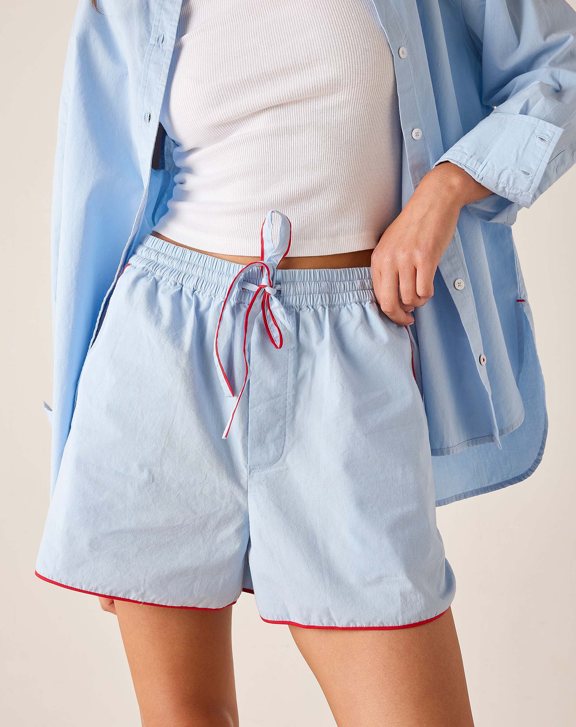 Light blue shorts with a red drawstring worn by a person on a beige background