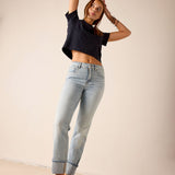 Woman wearing a black crop top and light blue jeans against a plain background