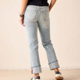 Person wearing light blue jeans with a plain background
