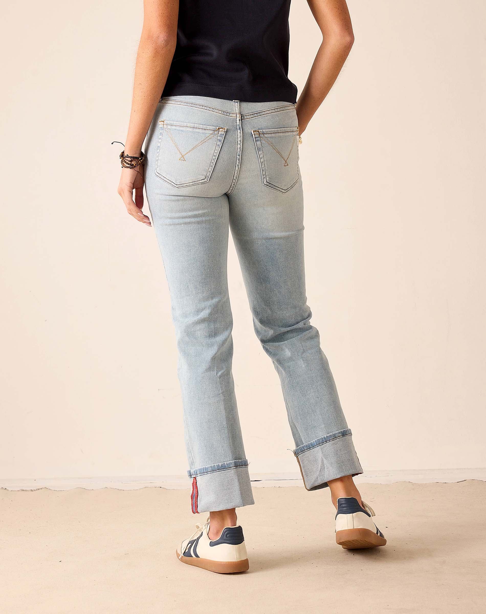 Person wearing light blue jeans with a plain background