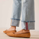 Light blue denim straight-leg pants with cuffed hems and contrast stitching, paired with mustard yellow suede loafers.