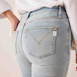 Back view of women's travel-friendly Cloud Nine light blue straight-leg denim jeans with a decorative gold-tone cursive stitching detail on the back pocket.