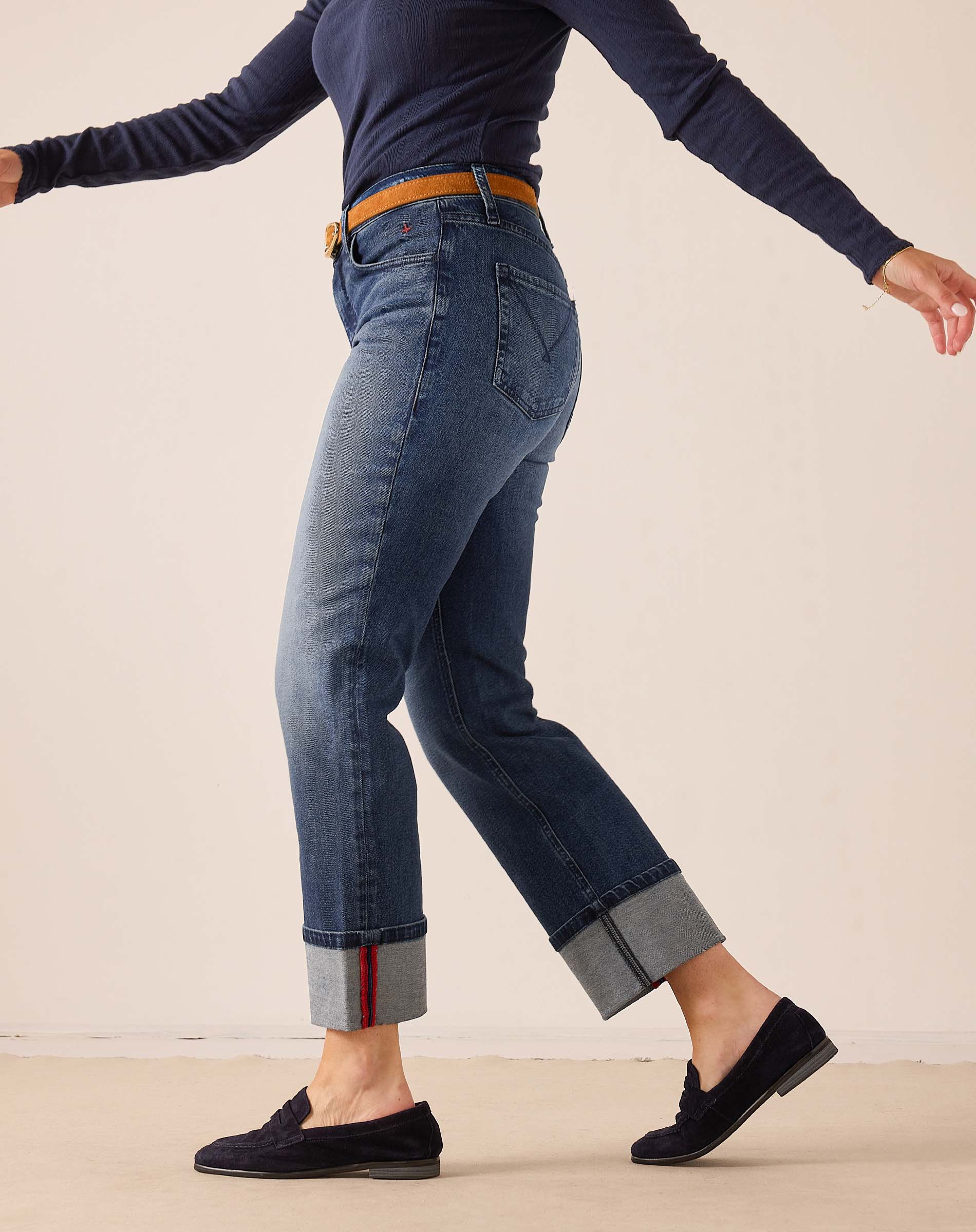 Faded indigo straight-leg denim pants with rolled hems and a decorative red stripe.