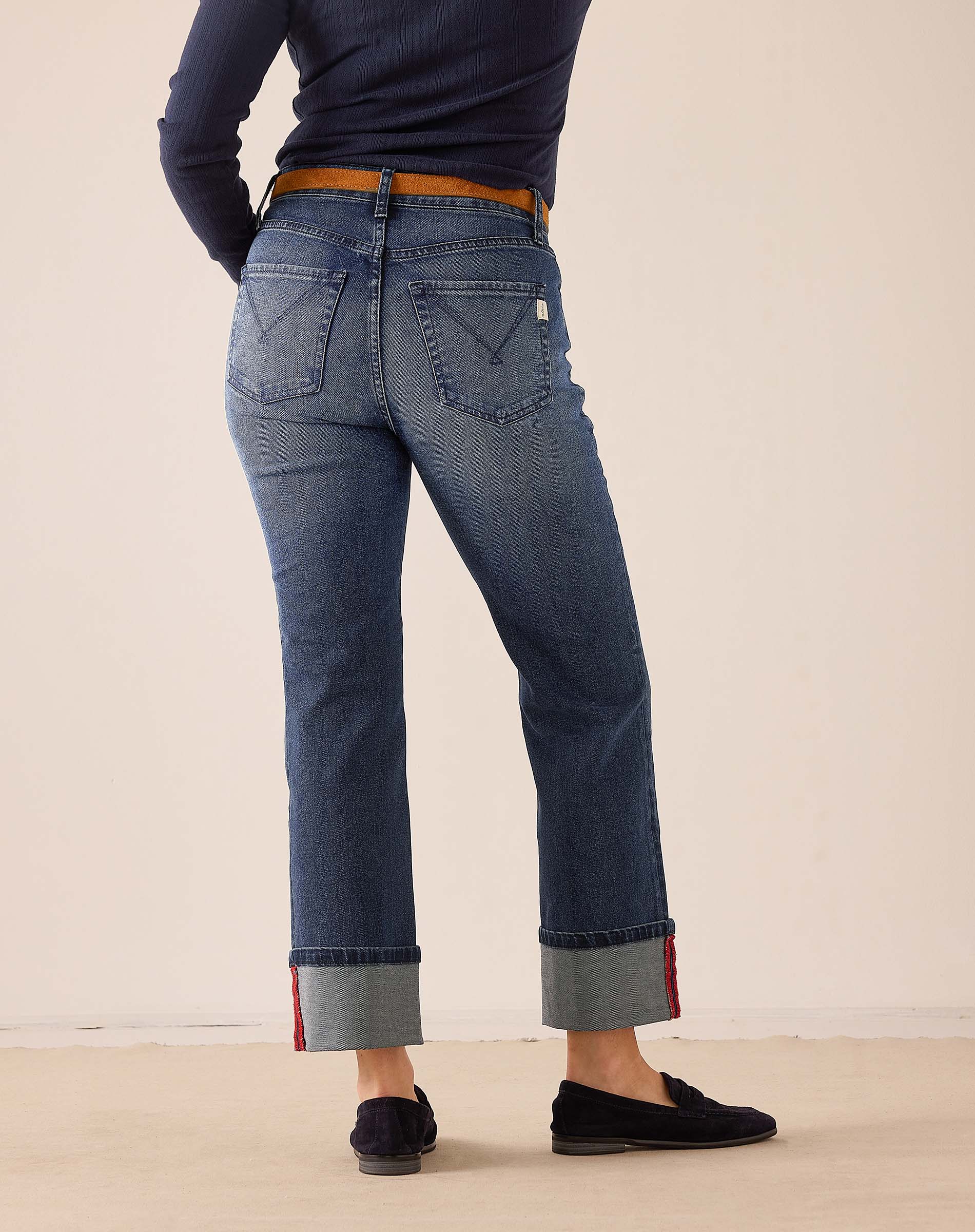 Faded indigo straight leg denim jeans with a cuffed hem and red stitching detail.