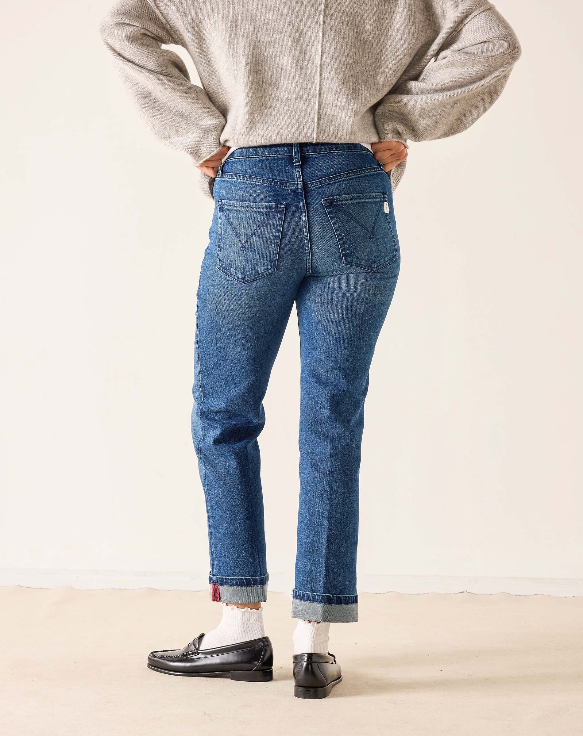Back view of women's travel-friendly faded ink blue straight-leg jeans with a cuffed hem.