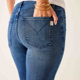 Person wearing blue jeans with a visible brand logo on a plain background