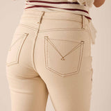 Back view of women's travel-friendly oat beige straight leg denim pants featuring distinctive stitching on the back pockets.