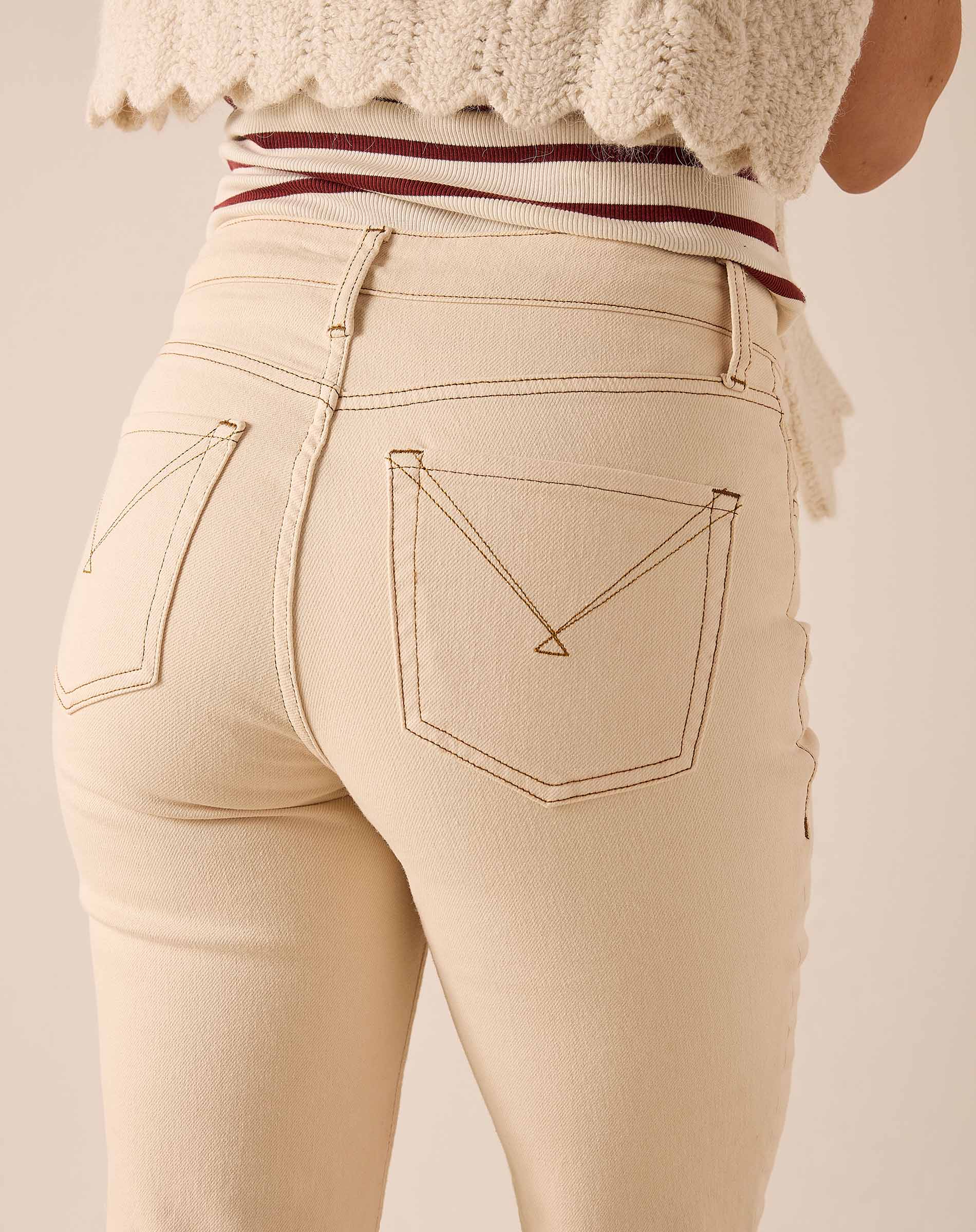 Back view of women's travel-friendly oat beige straight leg denim pants featuring distinctive stitching on the back pockets.