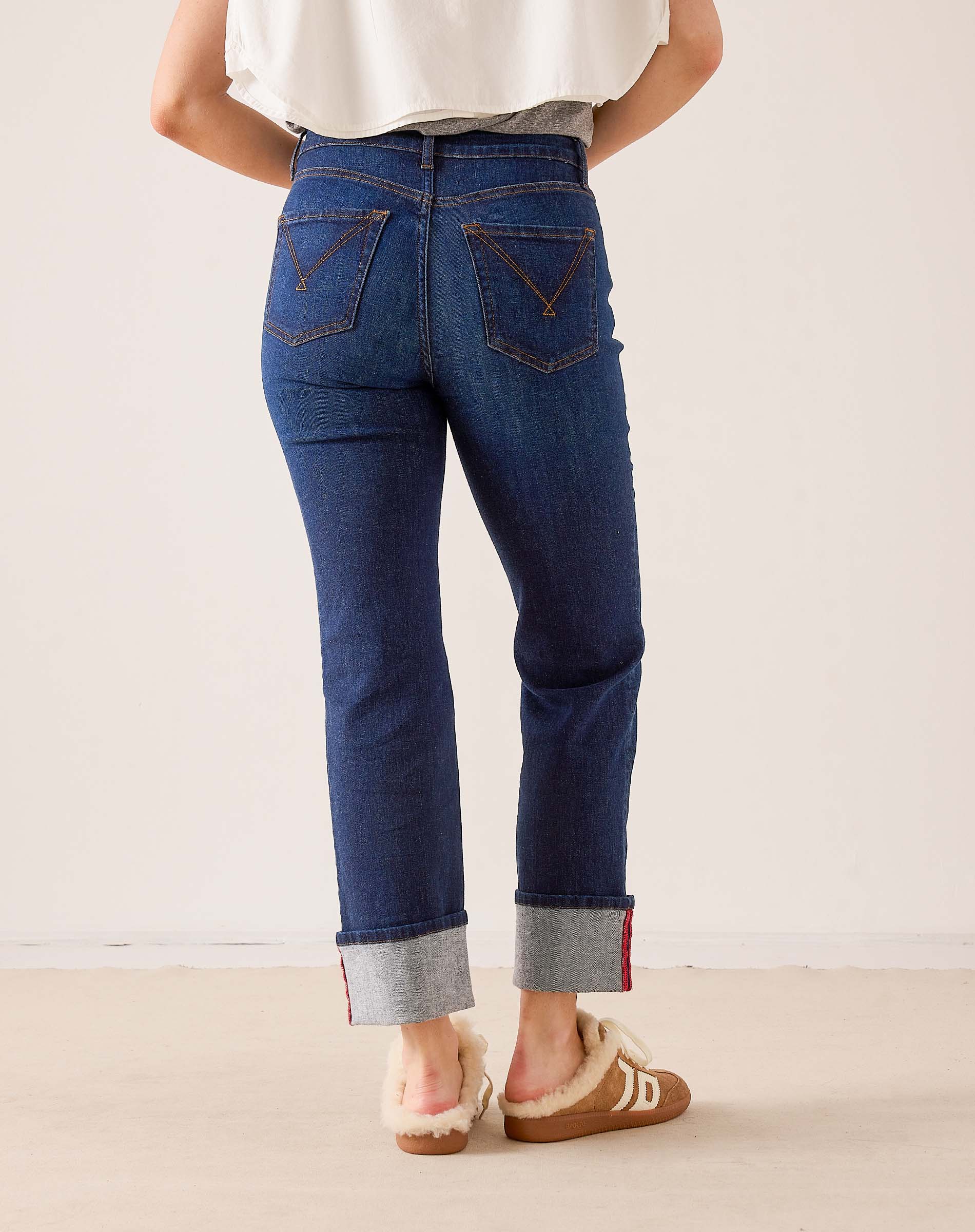 Dark blue rinse denim straight-leg jeans with cuffed hems and contrasting red stitching.