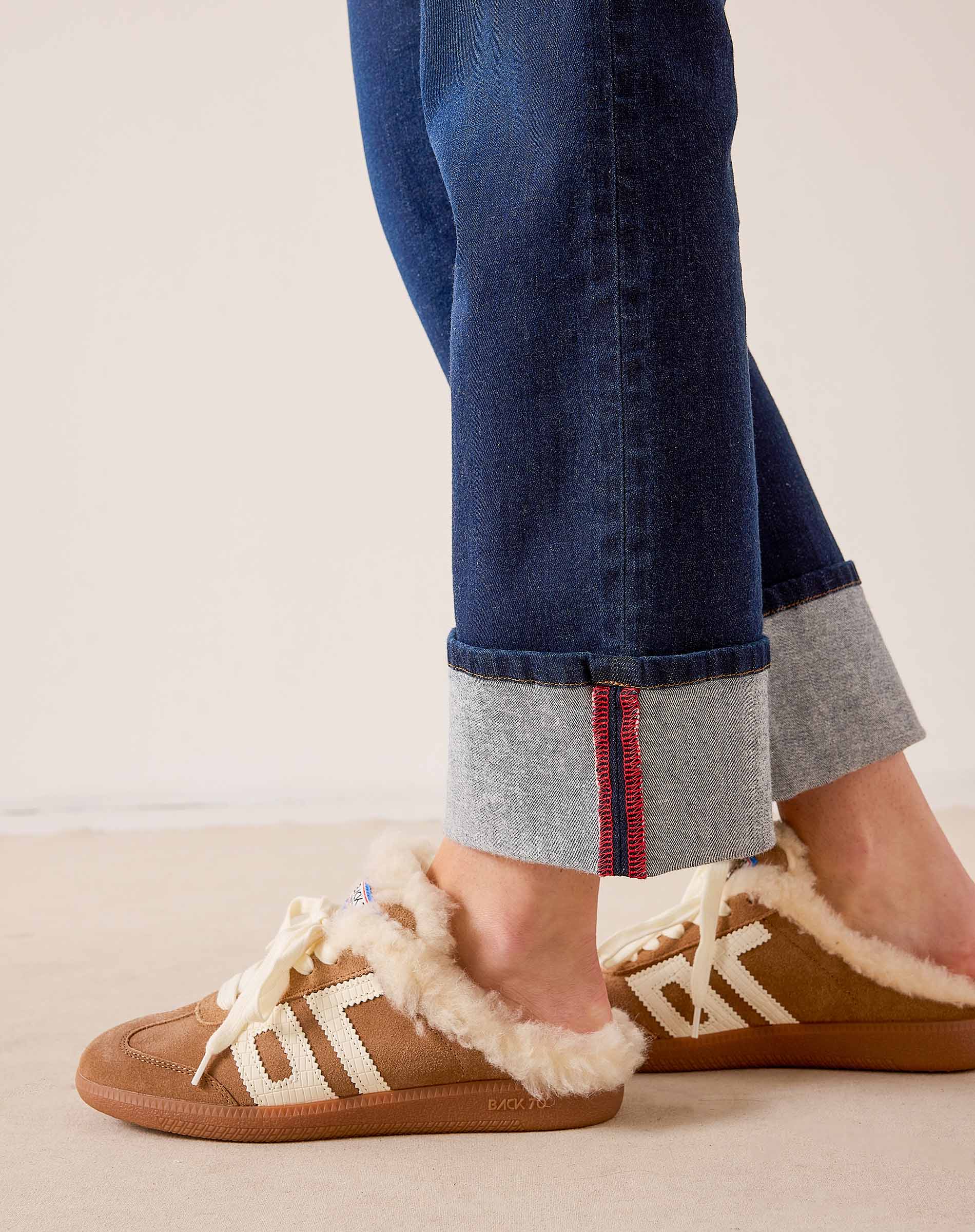 Rinse blue straight-leg denim jeans with cuffed hems and cozy cream-colored shearling-lined slippers.