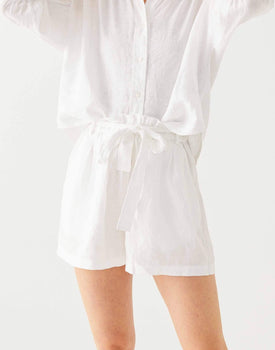 close up of female wearing white linen shorts with belt and matching top on a white background
