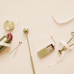 collection of several brass candle items laying on a white background with white ribbon