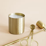 Brass candle sitting next to a brass snuffer and candle trimmer