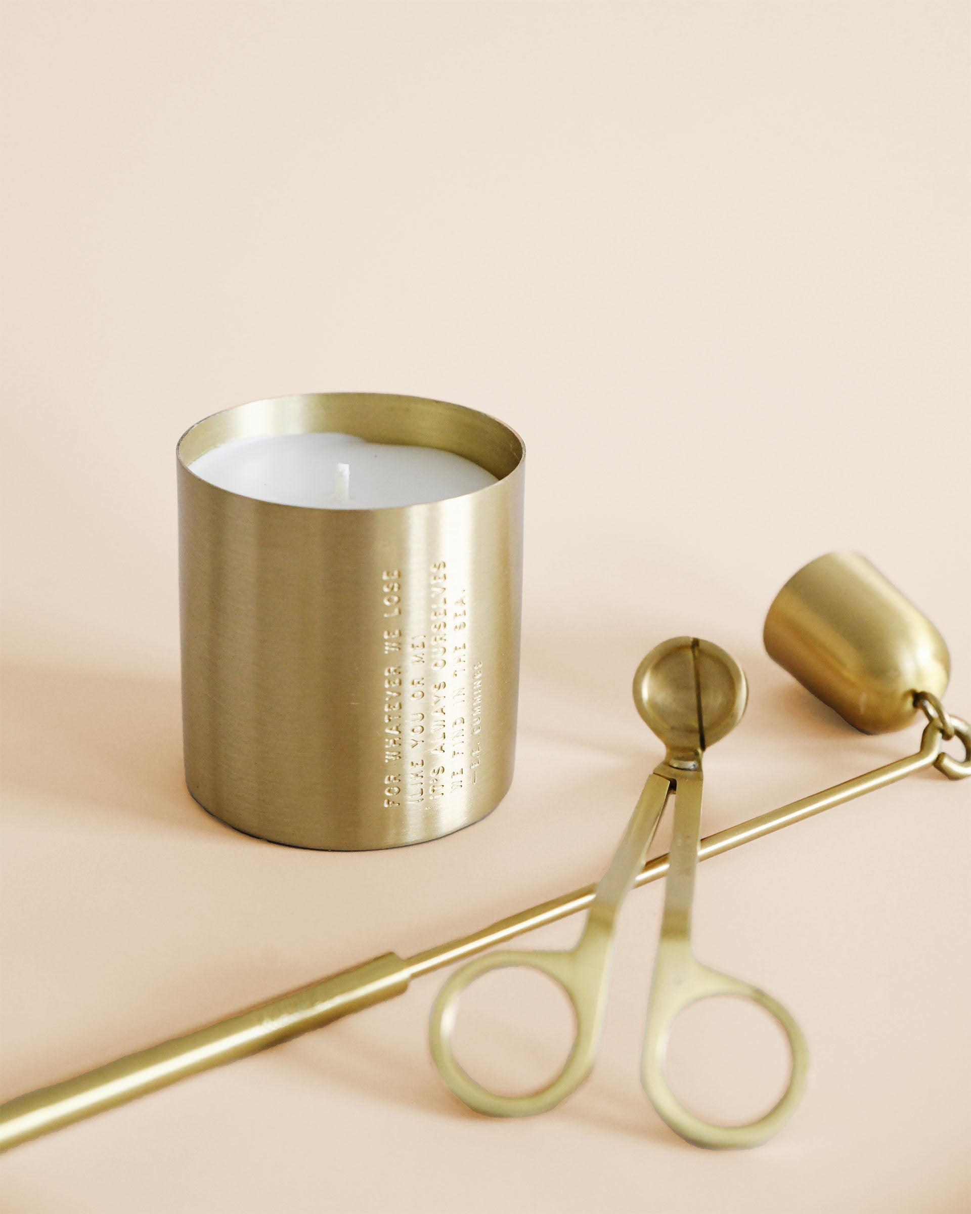 Brass candle sitting next to a brass snuffer and candle trimmer