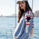 Light blue knit sweater with a contrasting white and red raglan sleeve featuring a large navy heart.