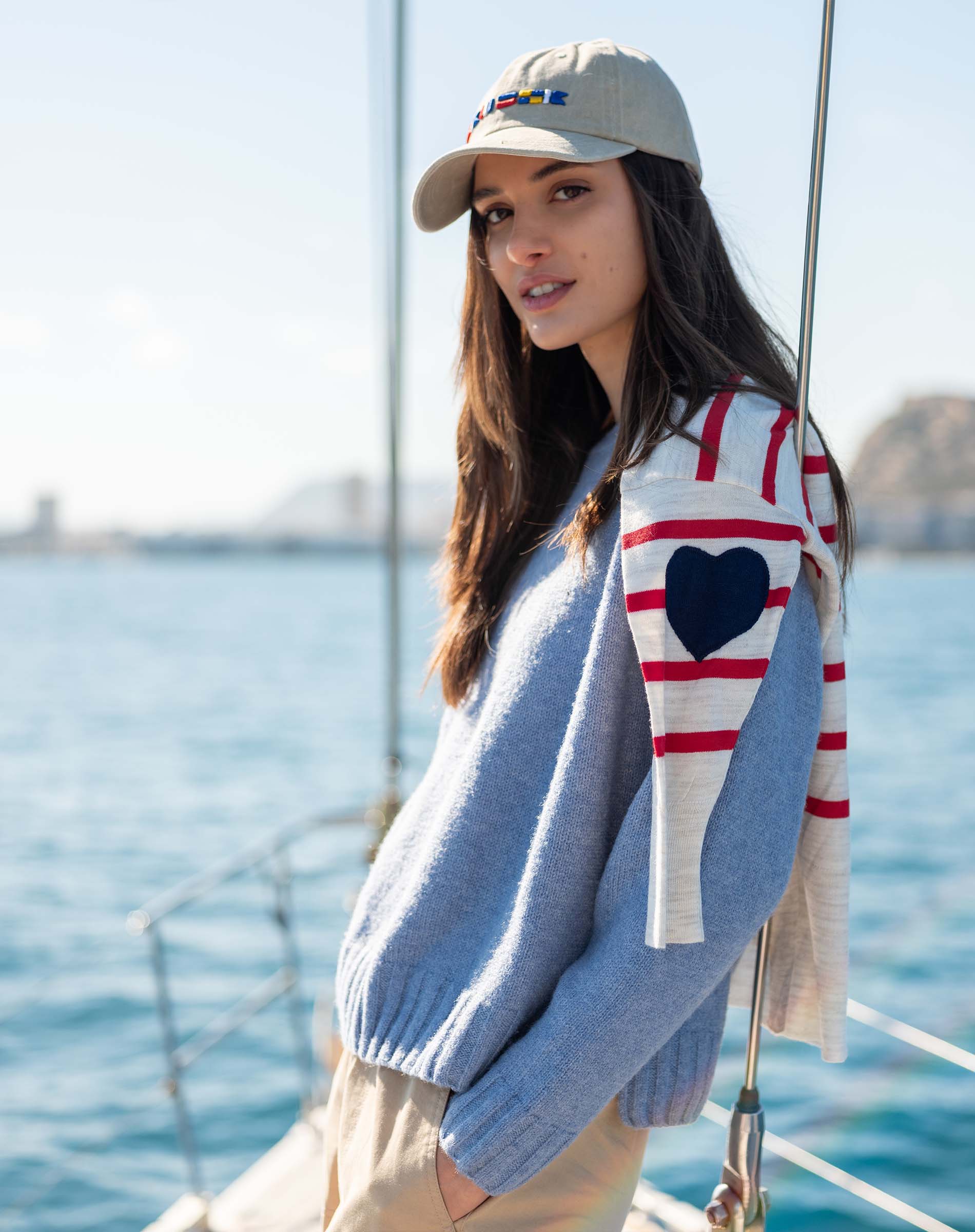 Light blue knit sweater with a contrasting white and red raglan sleeve featuring a large navy heart.