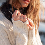 Cream cable knit sweater with chunky texture and long sleeves.
